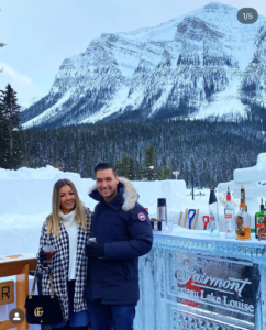 Matt Holt poses in front of a mountain in Banff, Canada with a woman.