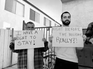 Holt Tenant Council members hold signs reading "I have a right to stay!" and "Right before the holidays, really?"