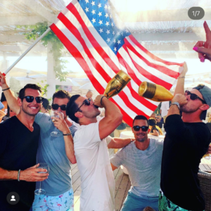 Matt Holt's Instagram post where he is drinking and celebrating with a group in St. Tropez, France. One member of the group is holding a flag of the United States.